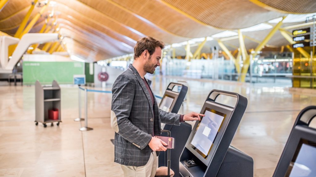 man at an airport check in kiosk printing a hard copy of his boarding pass